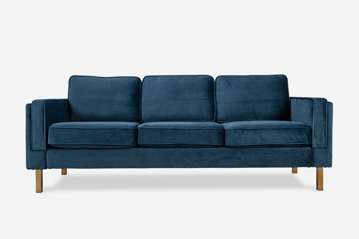 The Albany Sofa is a modern three-seater with deep blue velvet upholstery, three seat and back cushions, straight armrests, and wooden legs.