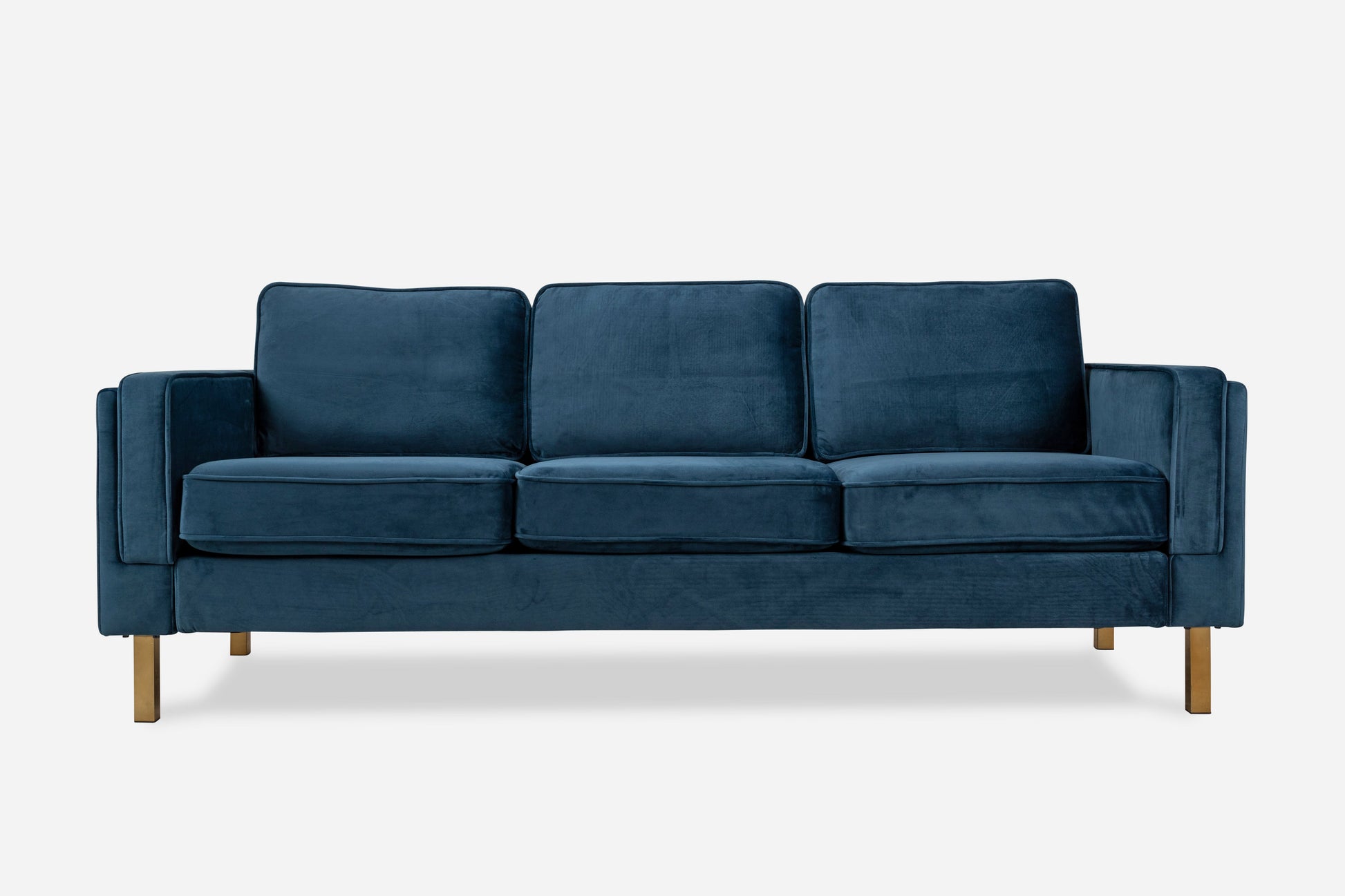 The Albany Sofa is a modern three-seater with deep blue velvet upholstery, three seat and back cushions, straight armrests, and wooden legs.