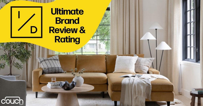 A cozy living room features a mustard yellow sectional sofa adorned with cushions and a throw blanket. In front is a round wooden coffee table. Large windows let in natural light, and a modern floor lamp stands on the right. Text overlay: "Ultimate Brand Review & Rating.