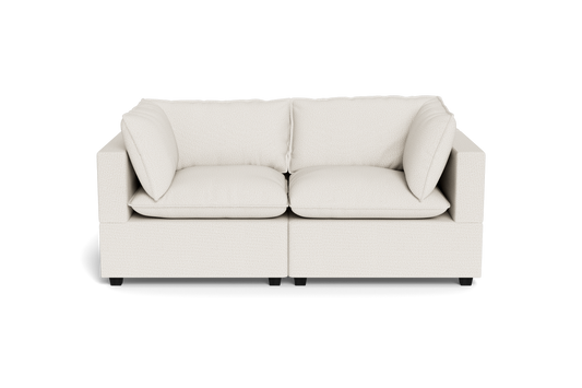 The Kova Pillow Cushion Sofa 86" is a modern, light beige two-seater with square armrests and plush cushions, shown from the front against a plain black background.