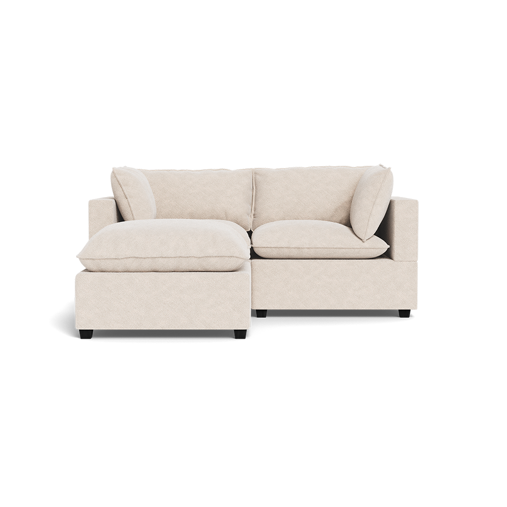 The Kova Pillow Cushion Sofa 86" + Ottoman features a modern, light beige design with plush cushions, a left-side extended chaise, low square arms, minimalist style, and dark short legs.