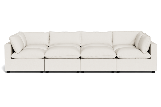 The Kova Pillow Cushion Grand Pit is a modern, large white sectional sofa featuring six seat cushions and six matching back pillows, shown from the front against a plain black background.