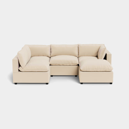 The Kova L Shape with Ottoman is a modern beige sectional sofa with cushions and low armrests, set on a plain light background.
