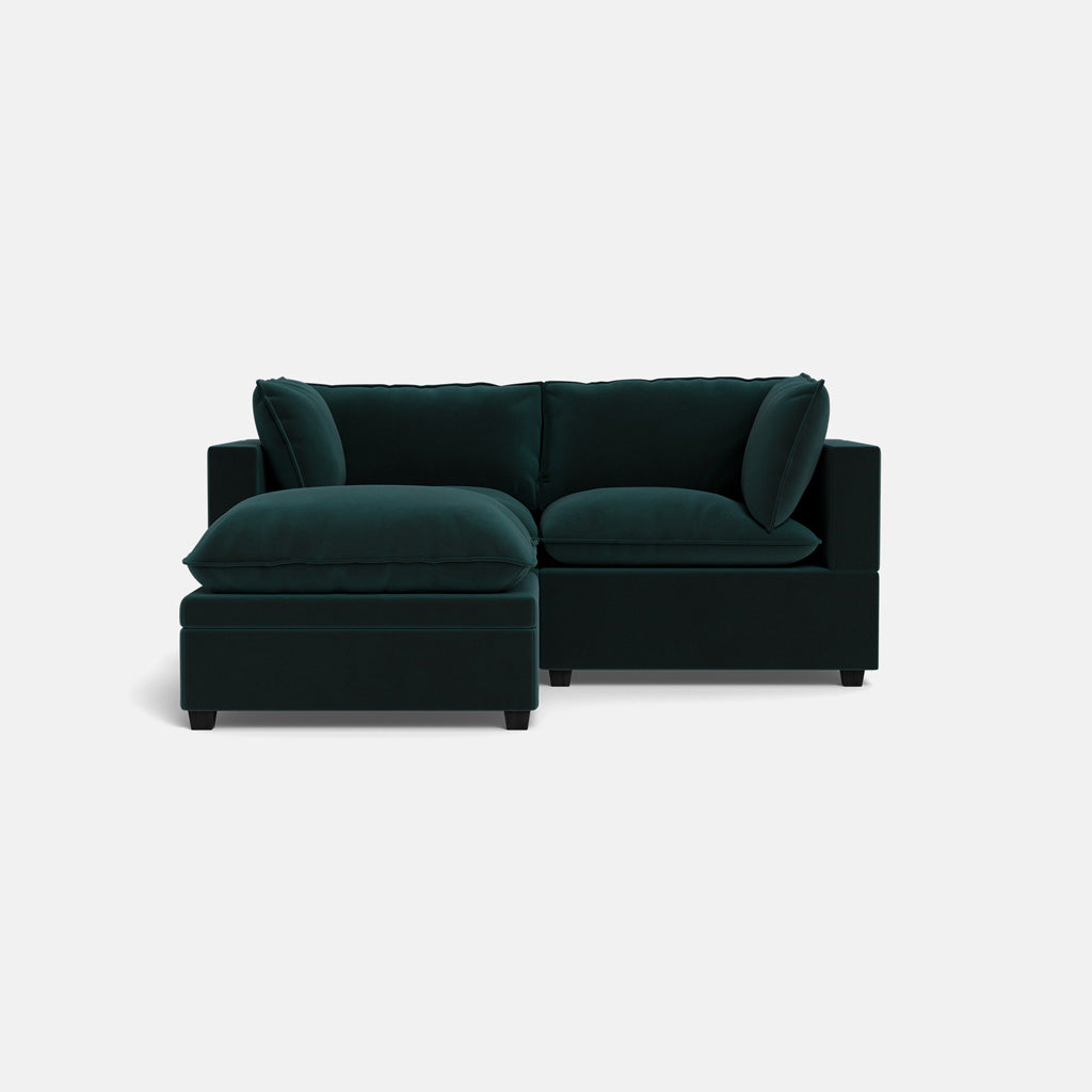 The Kova Pillow Cushion Sofa 86" + Ottoman in dark green features plush cushions and a left-facing chaise lounge, set against a plain white background.
