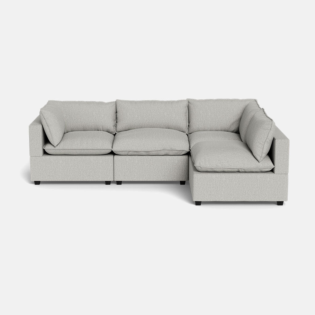The Kova Pillow Cushion L-Shape sectional sofa in light gray features three seat cushions on the left and a right-side chaise, with plush back and side cushions, shown on a plain white background.