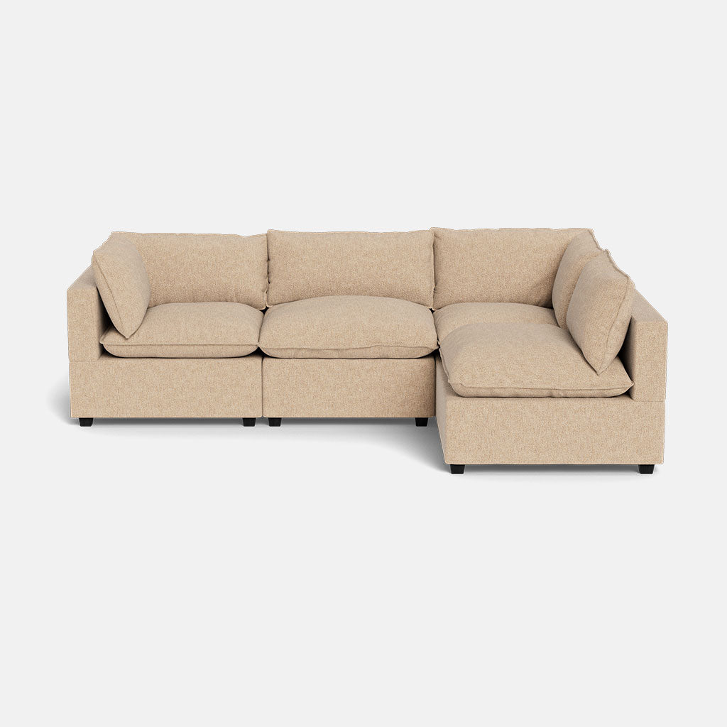 The Kova Pillow Cushion L-Shape is a beige L-shaped sectional sofa with three seat and back cushions plus armrests on both ends, shown against a plain white background.