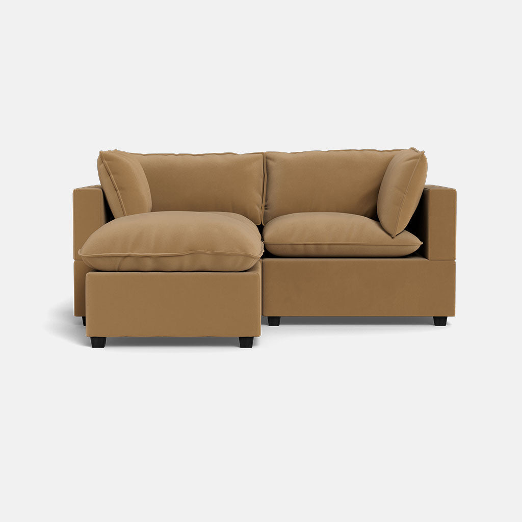 The Kova Pillow Cushion Sofa 86" + Ottoman, a modern tan sectional with plush cushions and a left-facing chaise lounge, is set against a plain white background.
