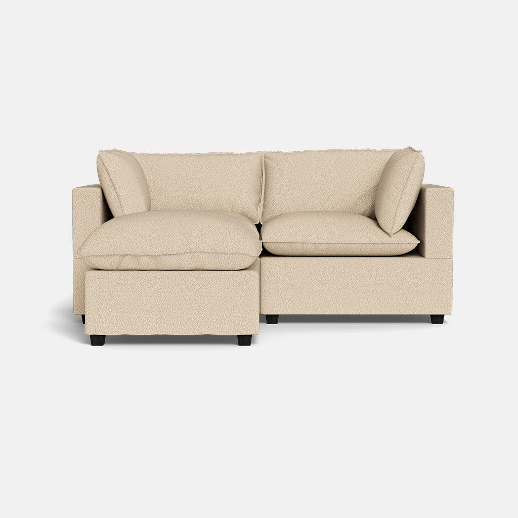 The Kova Pillow Cushion Sofa 86" + Ottoman is a modern beige sectional with three plush cushions and a left-side chaise, displayed on a plain white background.