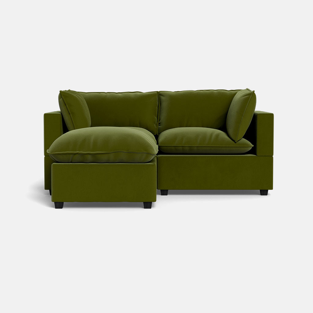 The Kova Pillow Cushion Sofa 86" in olive green features thick cushions, wide armrests, a left-facing chaise lounge, and comes with an ottoman, all set against a plain white background.