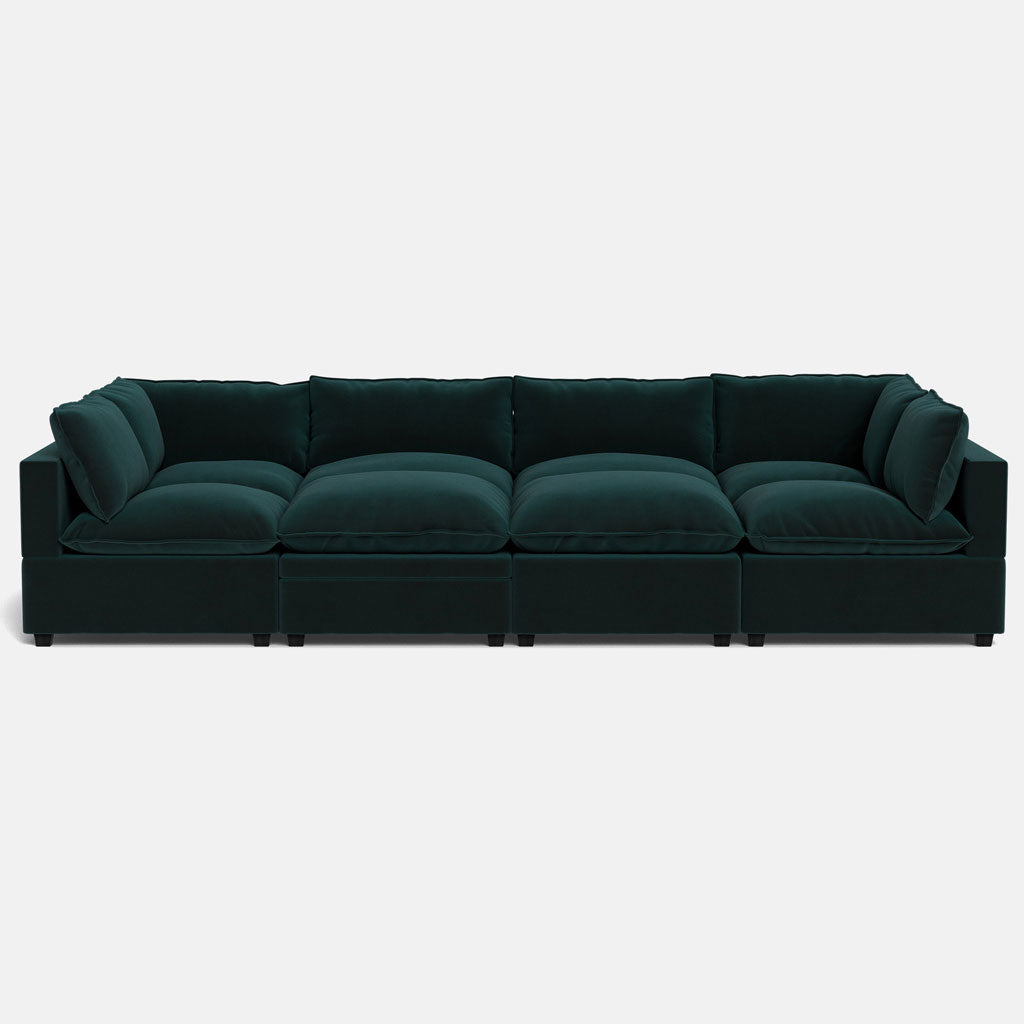 The Kova Pillow Cushion Grand Pit is a modern sectional sofa in deep green with plush cushions and a low profile, shown from the front against a plain white background.