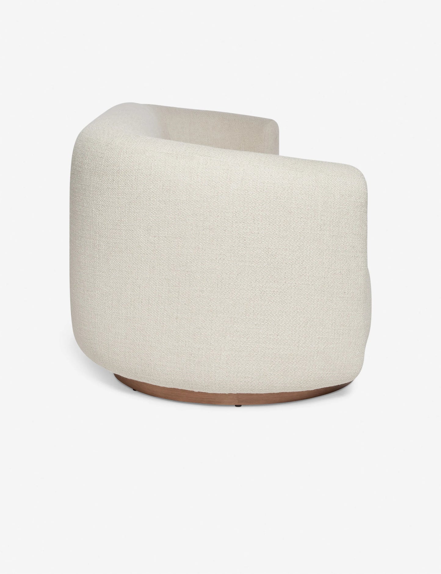 Side view of a contemporary, rounded beige fabric Lowry Sofa featuring a sleek wooden base against a plain white background. The sofa boasts a minimalist design and an upholstered texture.