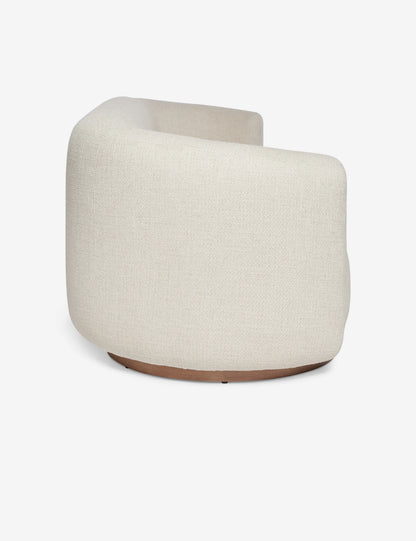 Side view of a contemporary, rounded beige fabric Lowry Sofa featuring a sleek wooden base against a plain white background. The sofa boasts a minimalist design and an upholstered texture.