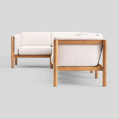 The Haven Sectional is a modern L-shaped sofa featuring an elegant wooden frame and off-white cushions. Its sleek, minimalist design makes it perfect for contemporary interiors, as seen against a plain gray background.