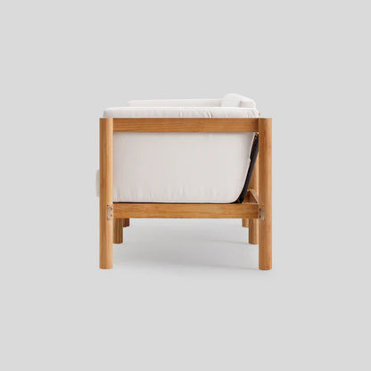 Side view of the Haven Sofa, a modern wooden armchair with white cushions set against a light gray background. It boasts a minimalist design with a sturdy wooden frame and legs.