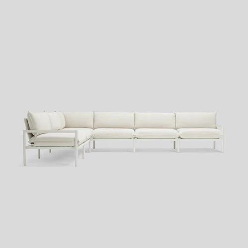 The Terra Sectional, a minimalist L-shaped sofa with a metal frame and plush white cushions, is set against a plain light gray background. The sofa consists of three sections that create a corner seating arrangement.