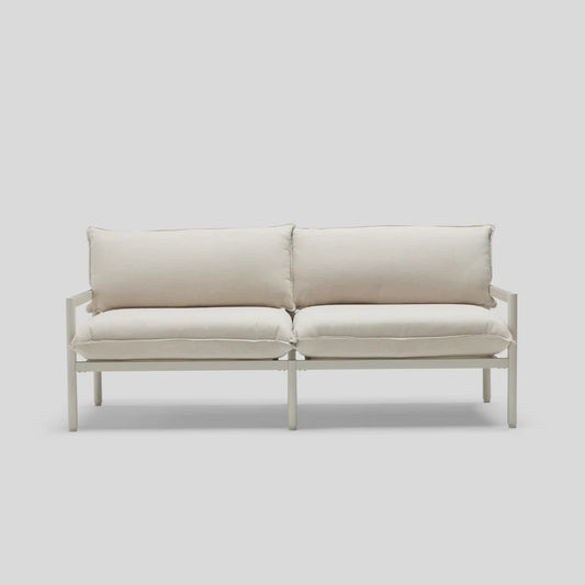A minimalist Terra Loveseat featuring a white design, metal frame, and plush cushions is set against a light gray background.