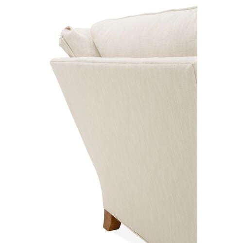 Close-up of the Brooke 6-Piece Left-Facing Sectional's corner, showcasing a sleek, angled backrest and a wooden leg. Its smooth, light-colored upholstery enhances the minimalist design.