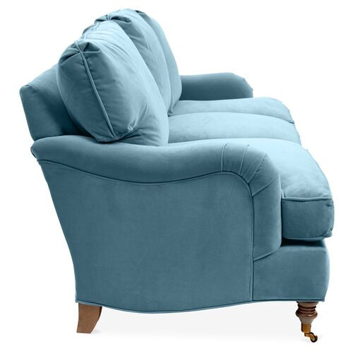 A side view of the Brooke 6-Seat Sofa in plush blue velvet, showcasing its two seat cushions and two back cushions. The sofa is designed with rounded arms and wooden legs.