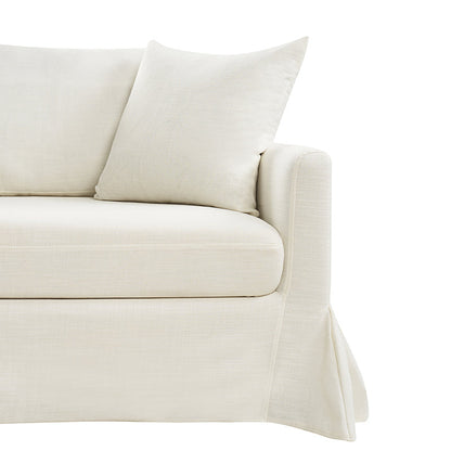 A close-up view of the Torsten Modern Comfortable Sofa in a cream color, featuring a skirted base and a matching cushion. The soft and plush fabric gives it a cozy and inviting appearance. The armrest is slightly rounded, set against a white background.