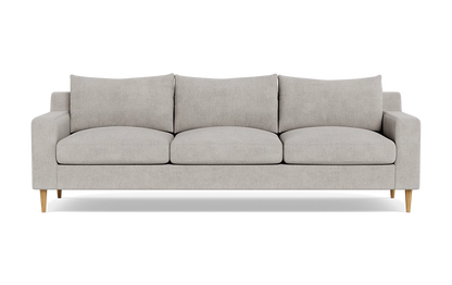 Introducing the Sloan Custom 3-Seat 95" Sofa, featuring a modern and minimalistic design with light gray upholstery. This three-seater has clean lines, cushioned backrests, and elegant wooden legs, all beautifully showcased against a plain black background.