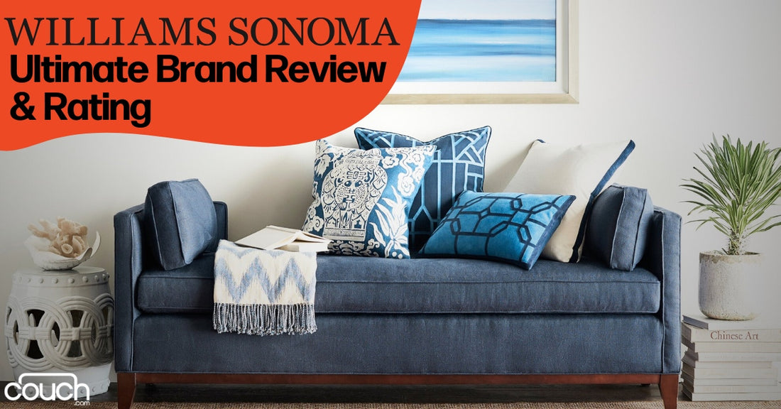 A modern living room with a blue sofa adorned with various patterned blue and white pillows. A blanket is casually draped over the arm. A potted plant and framed art piece decorate the serene space.