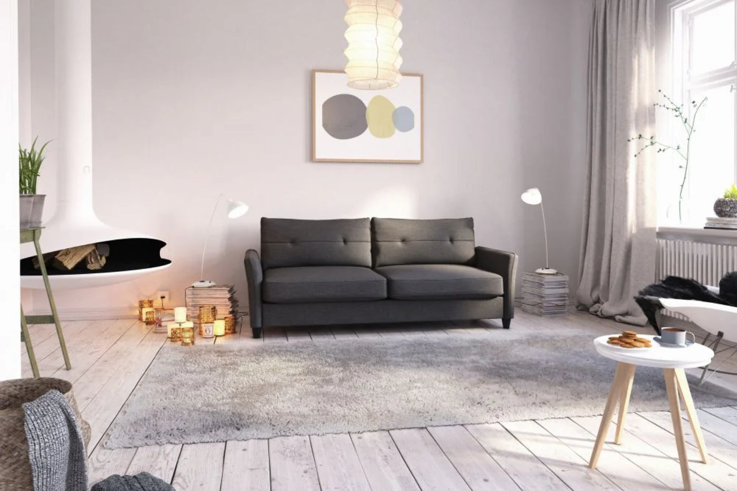 A cozy living room with a gray sofa, shaggy rug, and modern pendant light. White walls feature minimalist art. A small round table holds coffee and pastries. Floor lamps and stacked books add to the inviting ambiance.