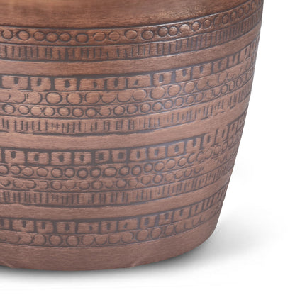 A close-up of the Johnsen Handcrafted Large Metal Accent Table in copper, showing horizontal rows of etched geometric patterns—squares, rectangles, and circles—on its surface against a white background.