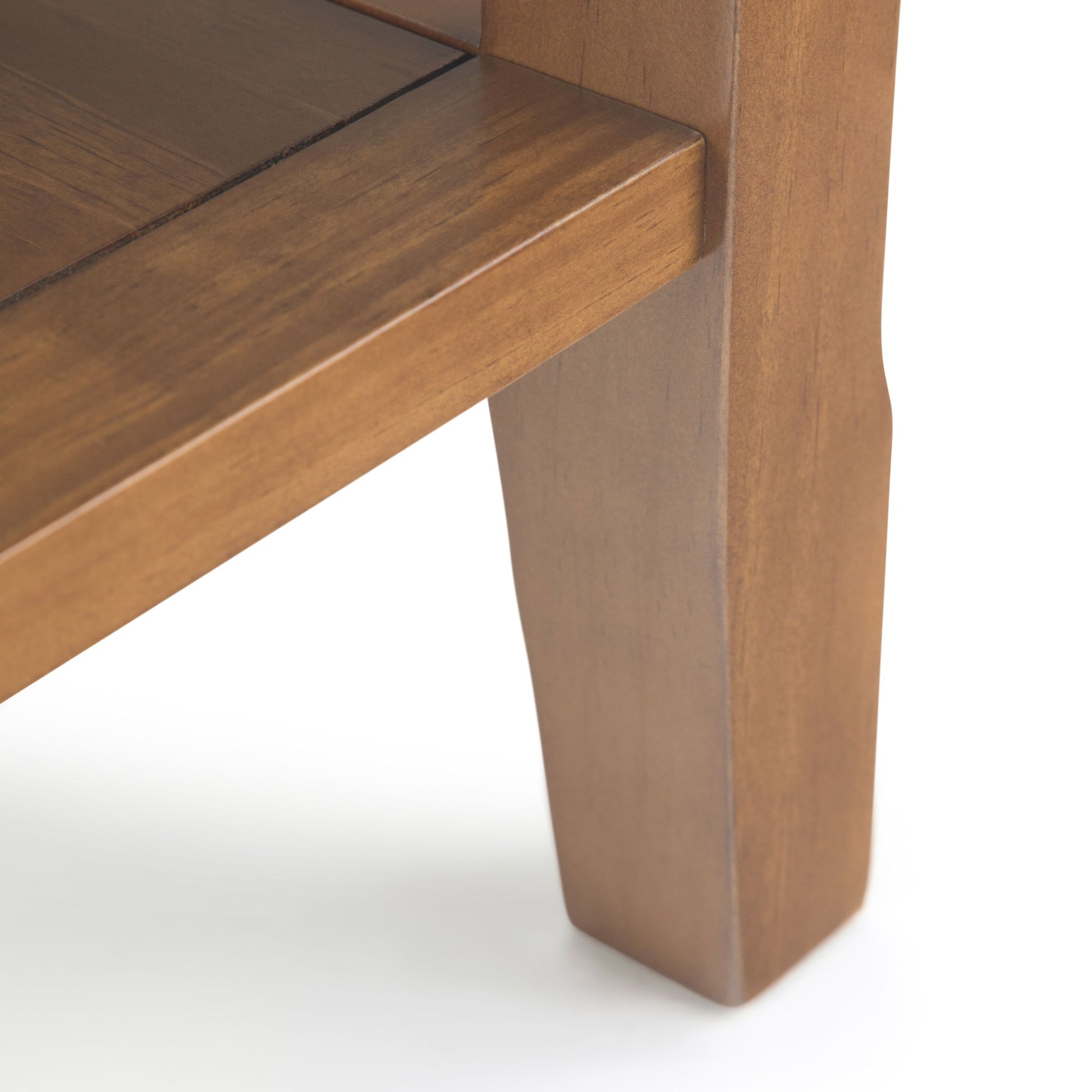 Close-up of the Acadian - Narrow Side Table, Handcrafted, highlighting the smooth brown wood grain and detailed joinery on its leg and corner against a white background.