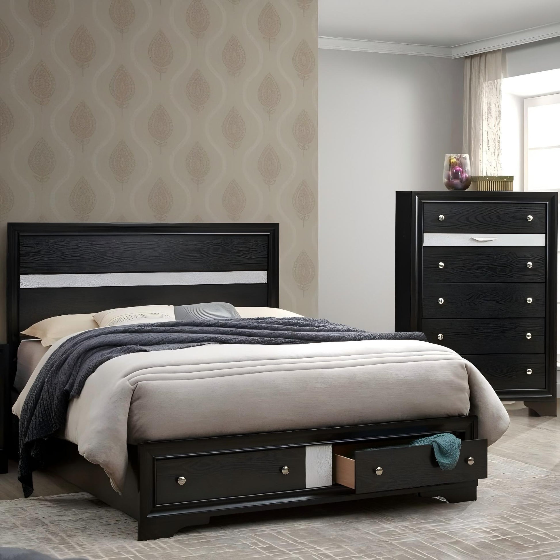 A modern bedroom with the Madrid Queen Bed in black, featuring storage drawers with nickel handles and gray bedding. A matching tall dresser, light patterned wallpaper, and natural window light complete the space.