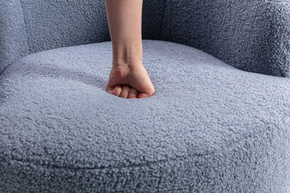 A person presses their fist into the cushioned seat of the Teddy Fabric Swivel Accent Armchair Barrel Chair With Powder Coating Metal Ring, creating a visible indentation in its soft, light gray upholstery.