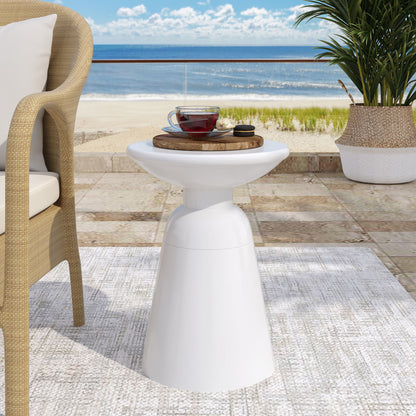 The Outdoor Modern Metal End Large Table, topped with a glass teacup and saucer on a wooden tray, stands near a wicker chair on the patio with a scenic beach view of sand, sea, and blue sky.