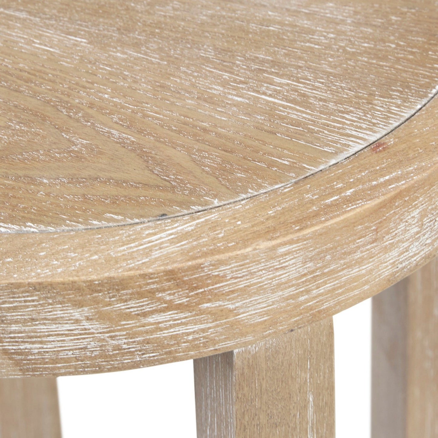 Close-up of the edge of the Accent Table Round Rustic Ash Veneer Reclaimed Wheat - Natural, highlighting its light, weathered finish, visible wood grain, and partially visible three-legged design.