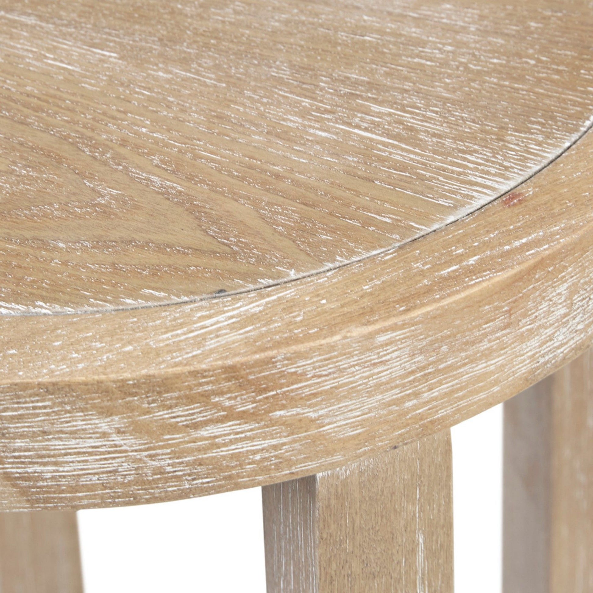 Close-up of the edge of the Accent Table Round Rustic Ash Veneer Reclaimed Wheat - Natural, highlighting its light, weathered finish, visible wood grain, and partially visible three-legged design.