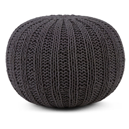 The Shelby - Handcrafted Hand Knit Round Pouf is a round, dark gray ottoman with chunky knit texture and thick vertical ribbing, shown on a white background.