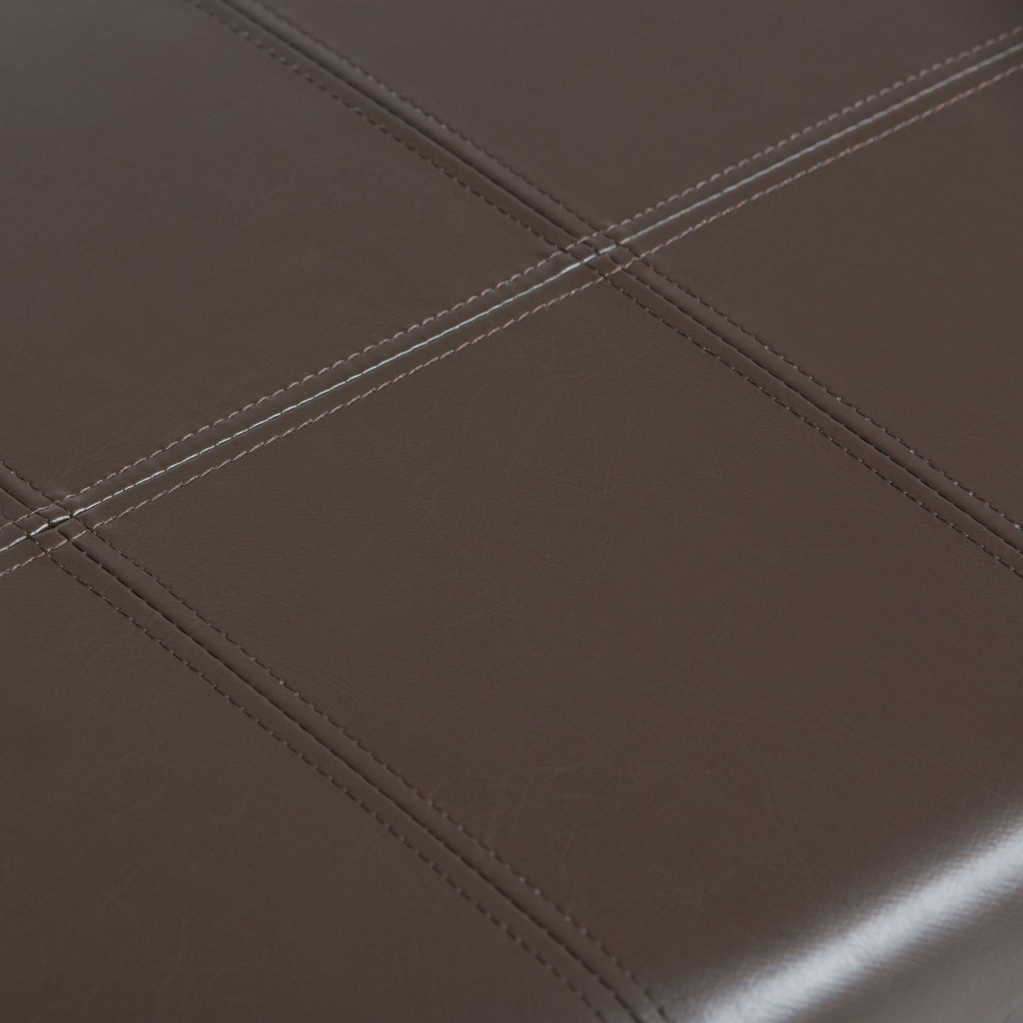 Close-up of the Dover - Upholstered Storage Ottoman Bench, featuring dark brown leather upholstery with visible stitching that forms a grid pattern of squares.