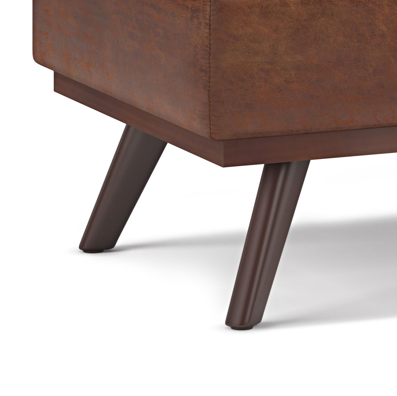 Close-up of the corner of the Owen Lift Top Large Coffee Table Storage Ottoman in brown upholstery, highlighting two angled dark wooden legs against a white background.