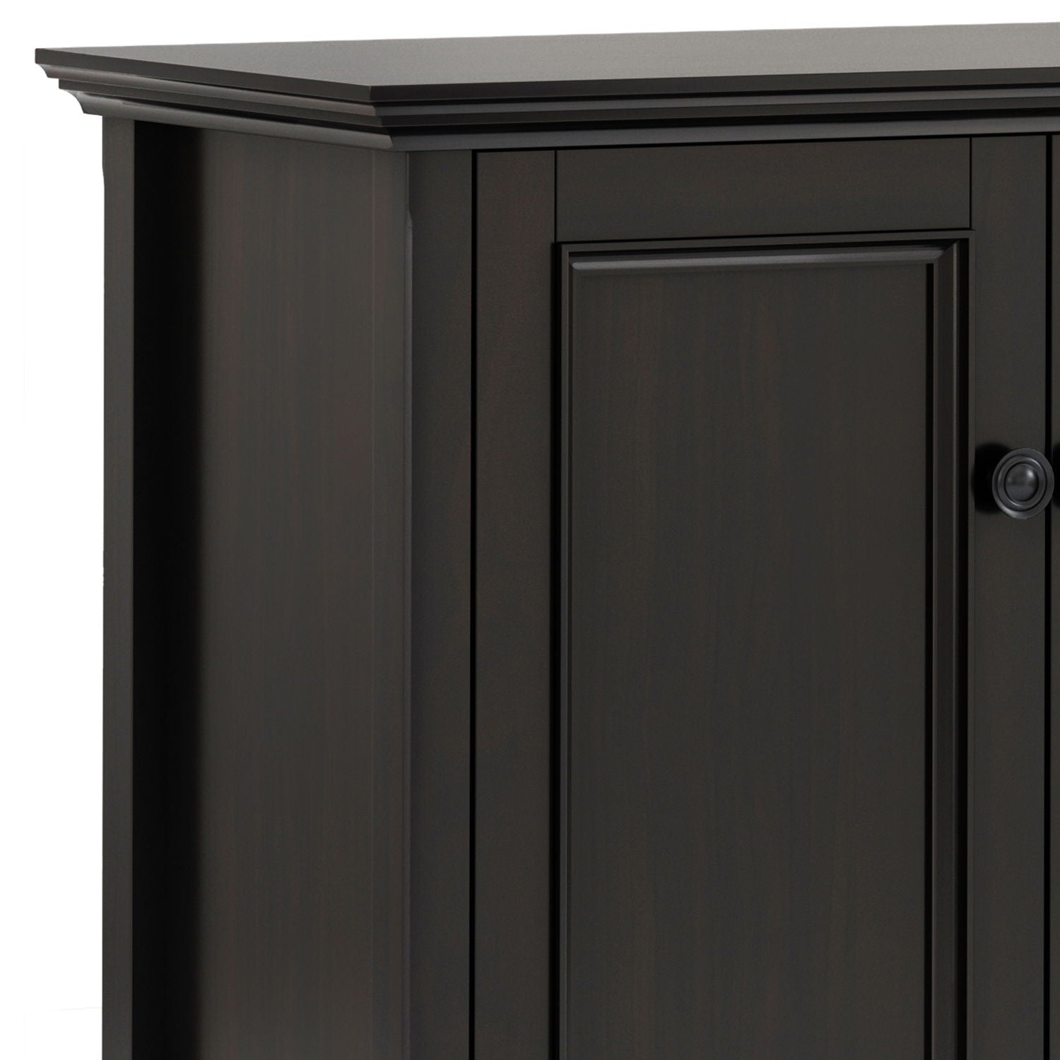 A close-up of the top corner of the Amherst - Wide 4 Door Storage Cabinet in Hickory Brown, showing its detailed trim, raised panel door, and a small round knob on the right side.