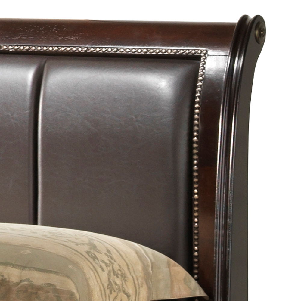 A close-up of the Lavita - Storage Bed's dark wood and leather-upholstered headboard with nailhead trim, shown beside a patterned beige pillow or comforter.