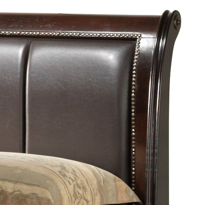 A close-up of the Lavita - Storage Bed's dark wood and leather-upholstered headboard with nailhead trim, shown beside a patterned beige pillow or comforter.