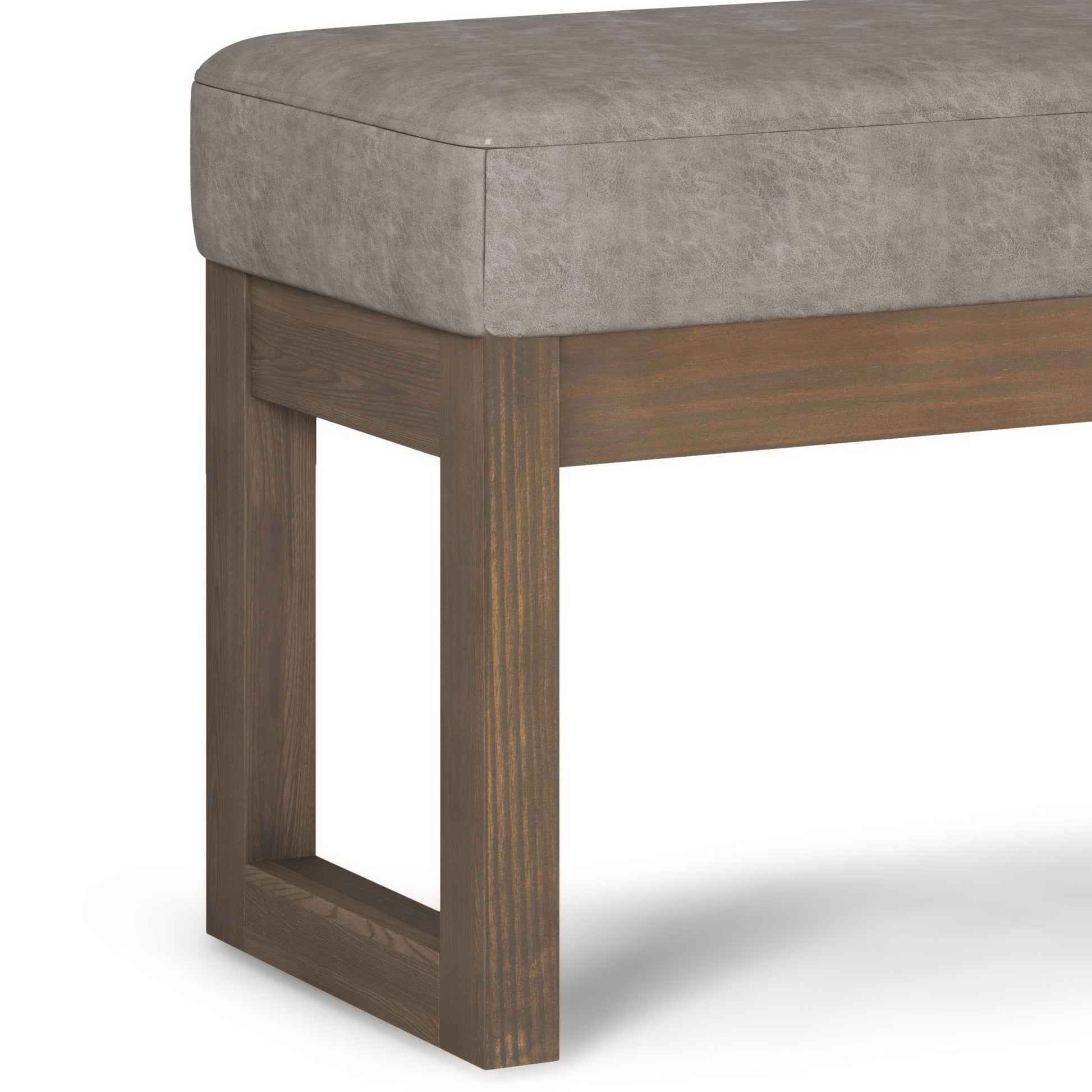 The Milltown Upholstered Ottoman Bench features a cushioned gray seat and a wooden base with rectangular legs and an open geometric design.