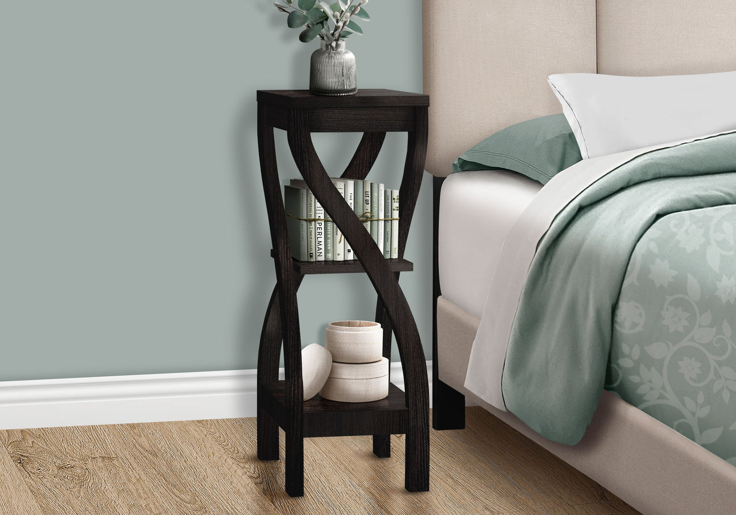 The Accent Table Versatile Usage, Square, Contemporary & Modern holds a plant on top, books on the middle shelf, and rolled towels below, placed next to a bed with green and white bedding.