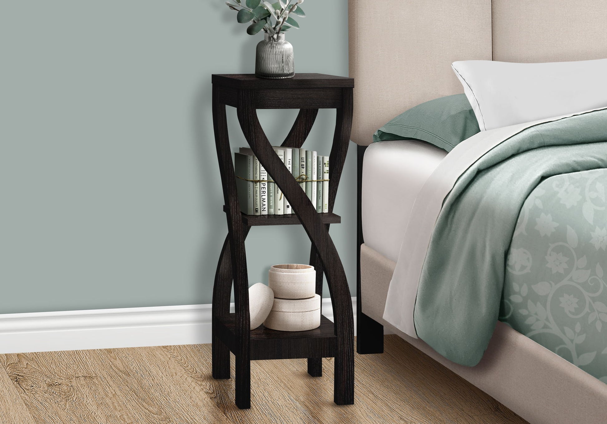 The Accent Table Versatile Usage, Square, Contemporary & Modern holds a plant on top, books on the middle shelf, and rolled towels below, placed next to a bed with green and white bedding.