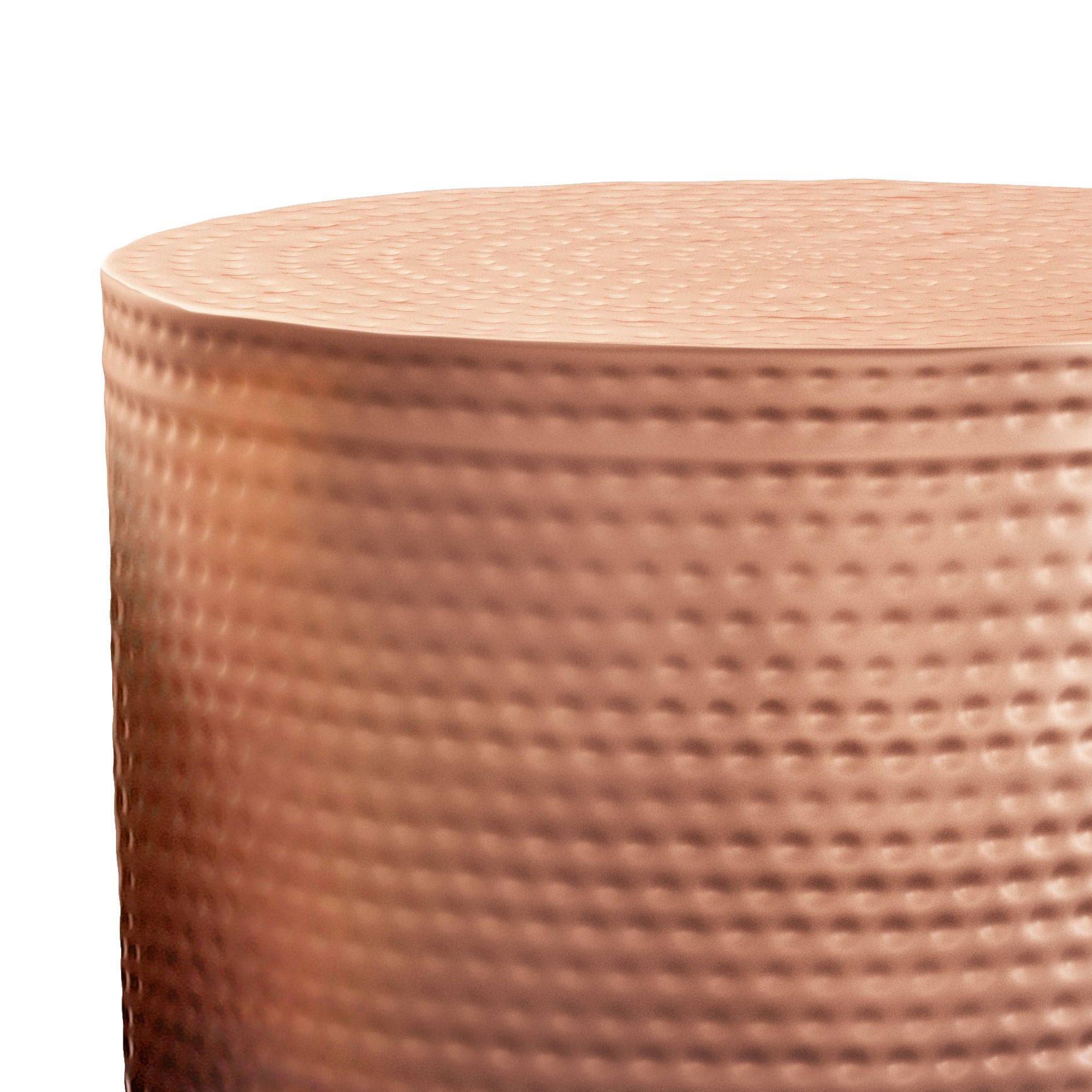 Close-up of the Nova Handcrafted Metal Side Table, featuring a cylindrical shape, copper finish, textured dimpled surface, and slightly uneven top edge. Lighting accentuates its metallic sheen and unique surface patterns.