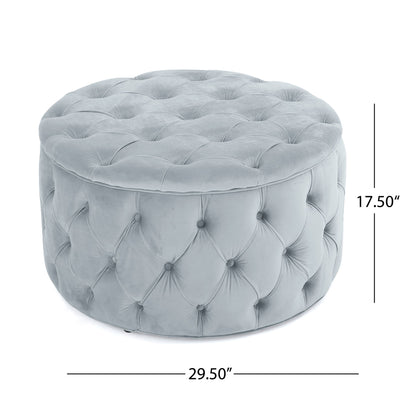 The Modern Glam Ottoman Velvet is a round, tufted ottoman in light gray with plush velvet upholstery, measuring 17.50"H x 29.50"W.