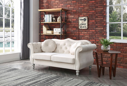 A stylish living room featuring the Stylish Flared Arm Loveseat, round cushions, a wooden side table with a plant, a metal bookshelf, a brick accent wall with a vintage "One Way" sign, and large windows with outdoor views.