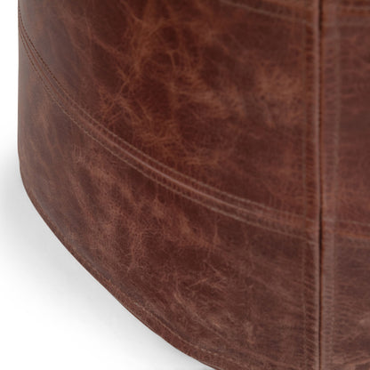 Close-up of the Connor - Handcrafted Round Pouf, featuring a brown leather surface with visible natural texture and stitching details.