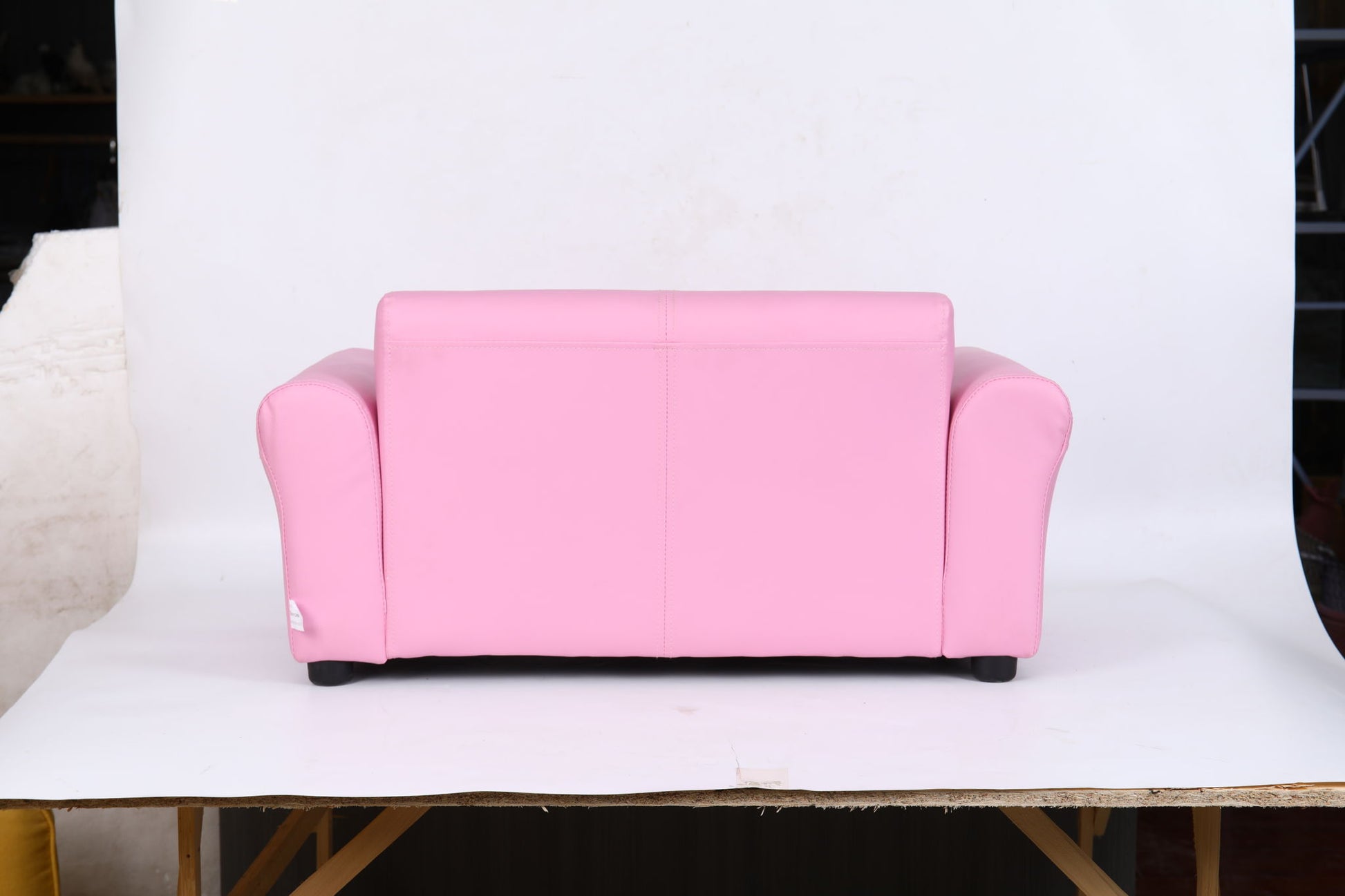 The Kids Club Chair Sofa / Sectional And Ottoman - Pink features a small, bright pink design with rounded arms and backrest, set on a wooden platform against a plain white background.