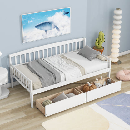 A Pine Wood Daybed With Two Storage Drawers, Sofa Bed With Bed Platform Of 10 Support Slats is topped with gray and white bedding and stuffed animals, set on a light wood floor with pastel decor, a floor lamp, cactus figurine, and whale wall art.