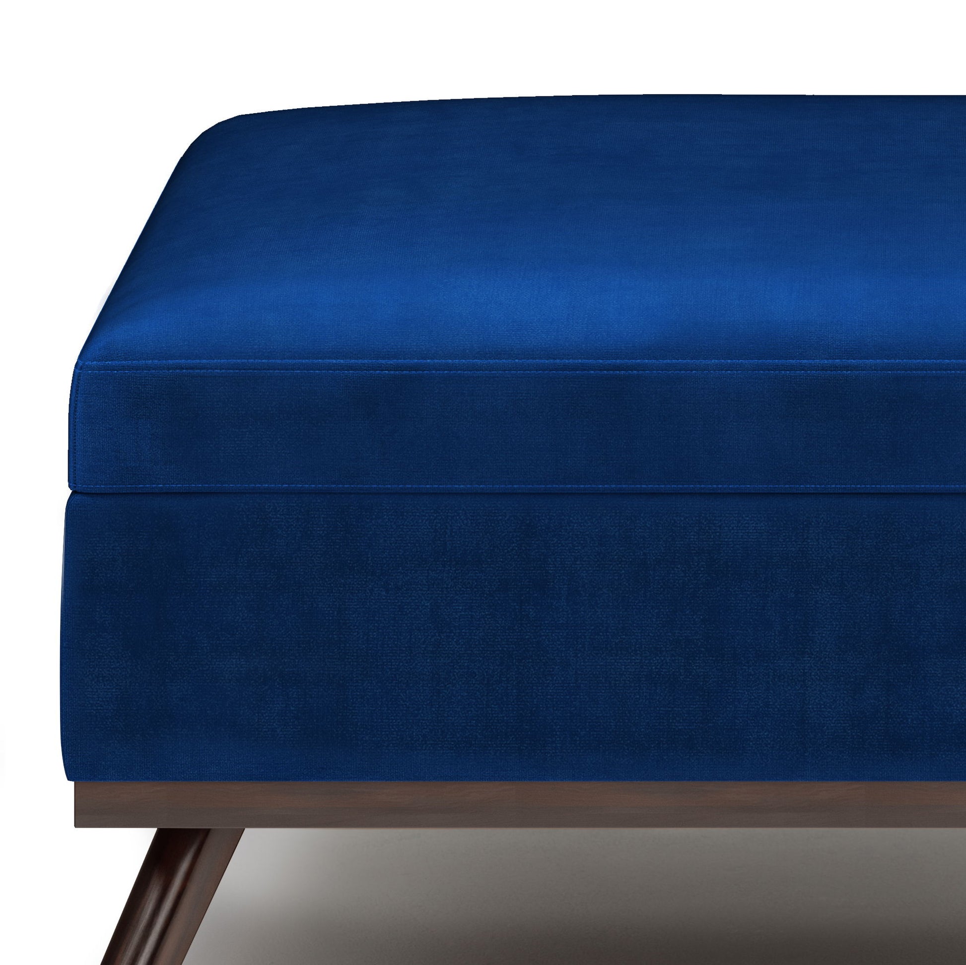 A close-up of the Owen Multifunctional Square Coffee Table Storage Ottoman, featuring deep blue velvet upholstery, a wooden base, and angled legs, set against a white background.
