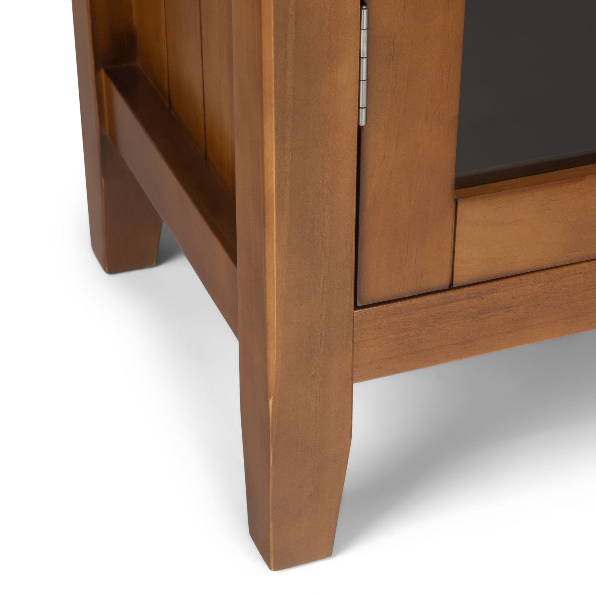 Close-up of the corner and legs of the Acadian - Medium Storage Cabinet, Handcrafted, highlighting its visible door hinge, smooth finish, and rich brown color.
